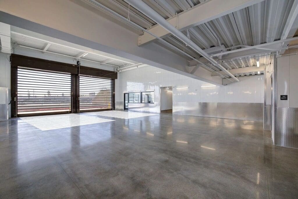 Spacious industrial indoor area with large windows.